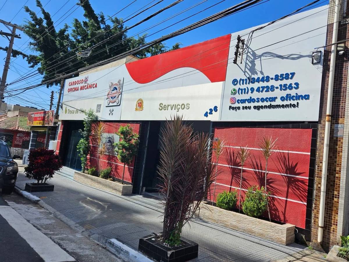 Fachada da Oficina Cardoso na R. Antônio Macedo: faixa vermelha e branca com o letreiro Cardoso Oficina Mecânica e os telefones.